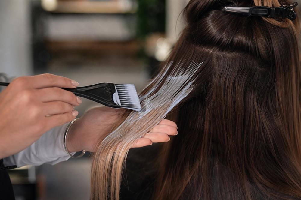 Hairstylist applying balayage colour to a strand of hair